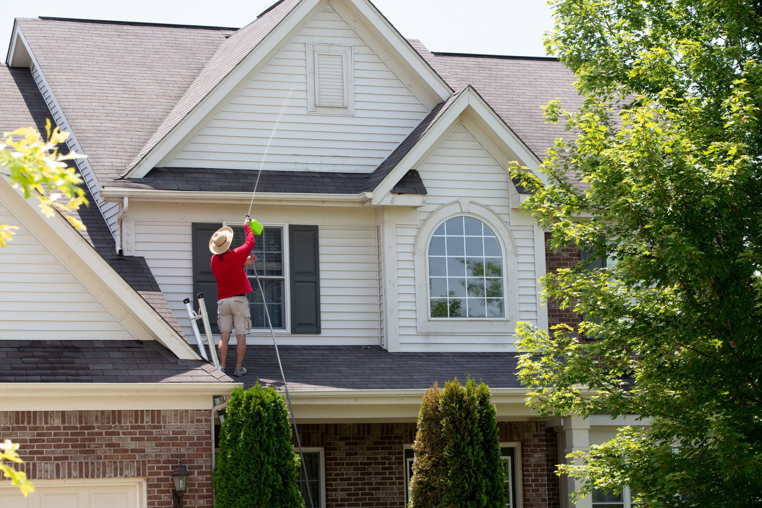 Man Cleaning The Upper Floor Exterior Of His Home