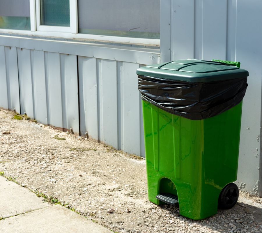 Green Plastic Garbage Container Standing In The Street