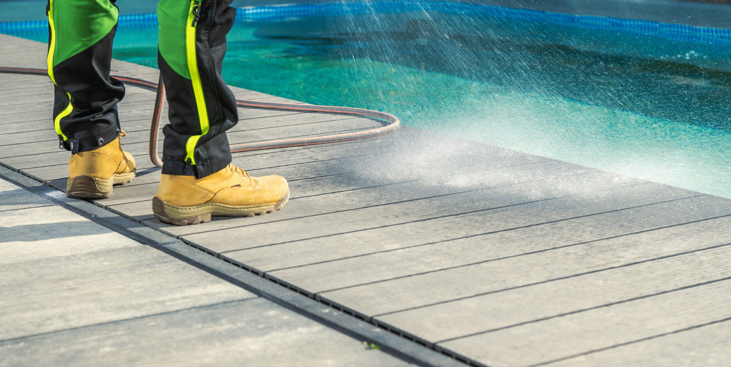 Man Cleaning His Poolside Deck With A Water